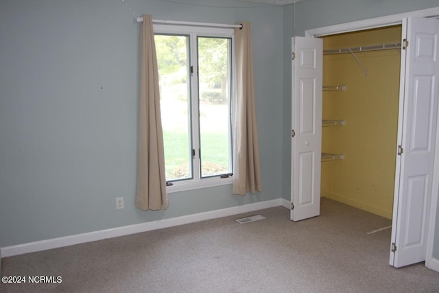 unfurnished bedroom with a closet, carpet floors, and multiple windows