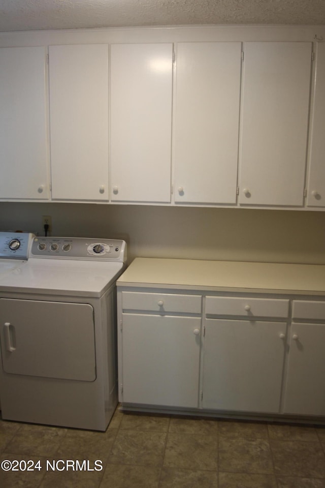 clothes washing area featuring washer / clothes dryer, a textured ceiling, and cabinets