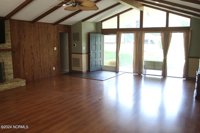 unfurnished living room with ceiling fan, a brick fireplace, dark hardwood / wood-style flooring, and wooden walls