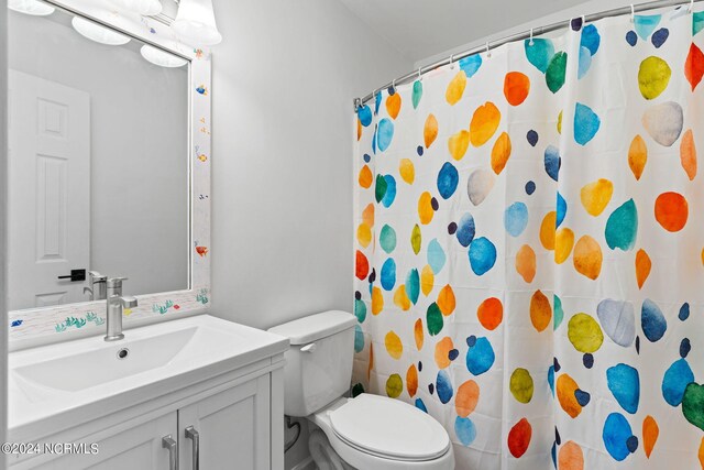 bathroom featuring a shower with shower curtain, vanity, and toilet