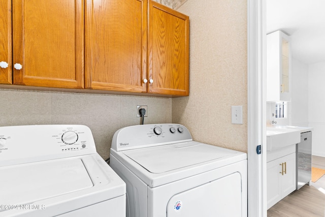 laundry area featuring light hardwood / wood-style flooring, cabinets, and independent washer and dryer