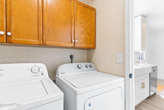 160 NE 5th St, Oak Island, NC 28465 - laundry area with independent washer and dryer, light wood-style flooring, and cabinet space