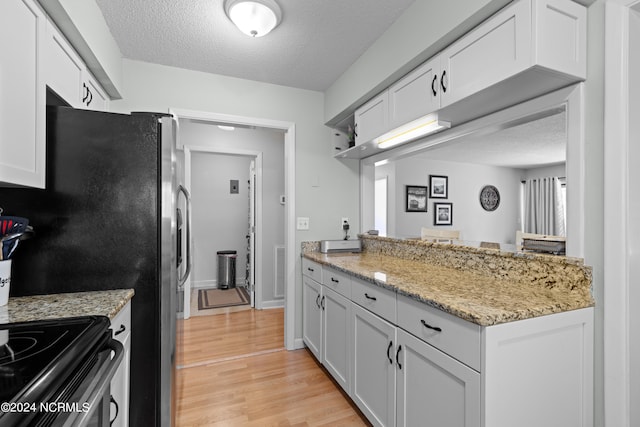 kitchen featuring white cabinets, light hardwood / wood-style flooring, and a textured ceiling