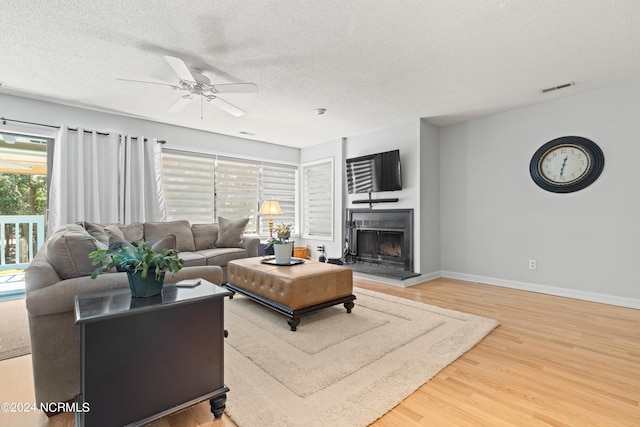 living room with hardwood / wood-style flooring, a healthy amount of sunlight, ceiling fan, and a textured ceiling