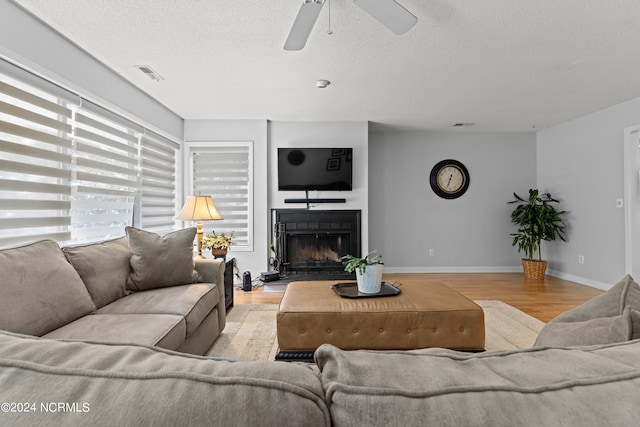 living room featuring a textured ceiling, ceiling fan, and light hardwood / wood-style flooring