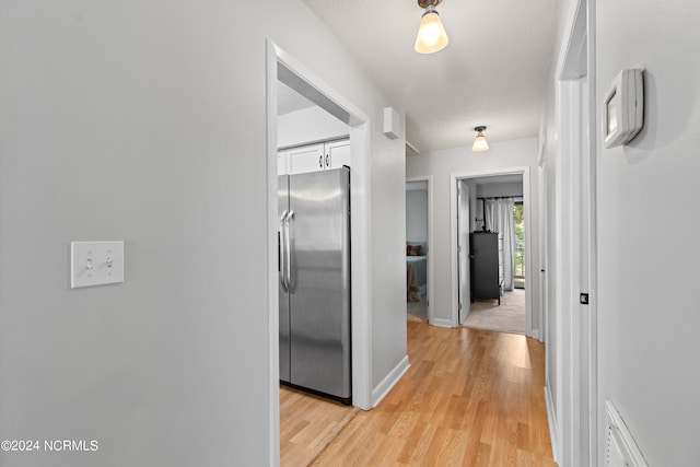 hall featuring light hardwood / wood-style flooring and a textured ceiling