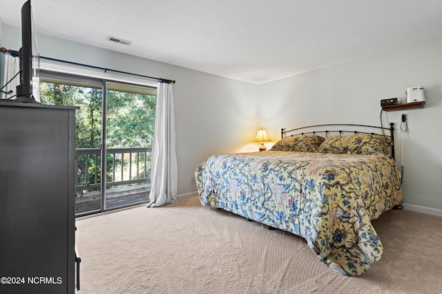 bedroom with access to outside, carpet flooring, and a textured ceiling