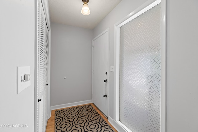 hallway with light hardwood / wood-style floors and a textured ceiling