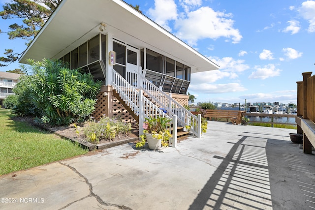 view of patio / terrace with a water view and a sunroom