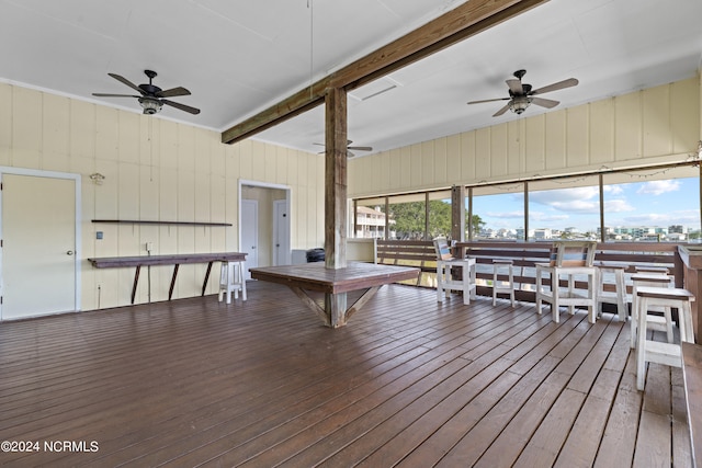 playroom with wood walls, wood-type flooring, beamed ceiling, and ceiling fan