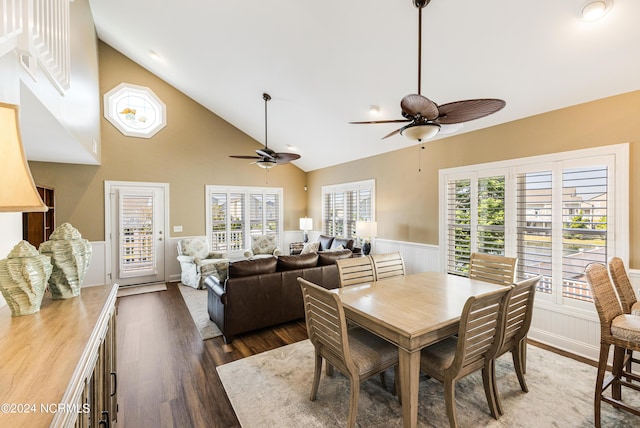 dining space with a ceiling fan, high vaulted ceiling, wood finished floors, and wainscoting