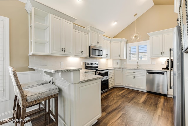 kitchen with decorative backsplash, white cabinetry, stainless steel appliances, and vaulted ceiling