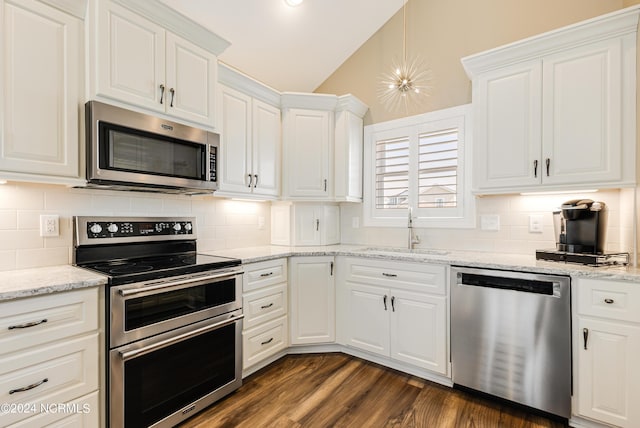 kitchen with a sink, stainless steel appliances, white cabinets, lofted ceiling, and dark wood-style flooring