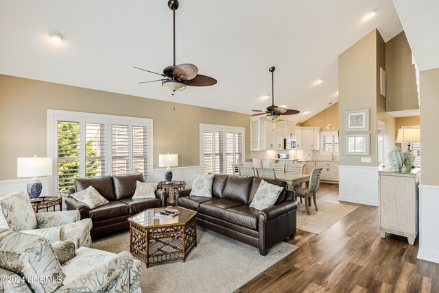 living room with built in shelves, hardwood / wood-style flooring, ceiling fan, and a high ceiling