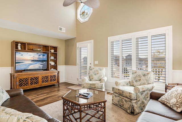 living area featuring a ceiling fan, wood finished floors, and wainscoting