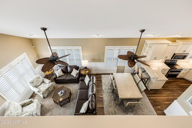 living room featuring ceiling fan, wood-type flooring, and a high ceiling