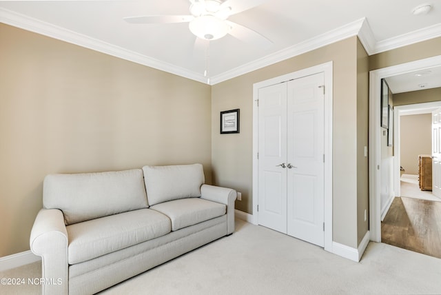 sitting room with light colored carpet, ceiling fan, baseboards, and ornamental molding