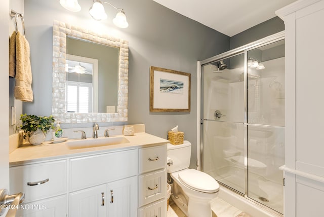 bathroom featuring a shower stall, toilet, vanity, and a ceiling fan