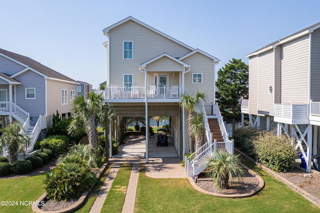 rear view of property with a lawn, driveway, stairway, covered porch, and a carport