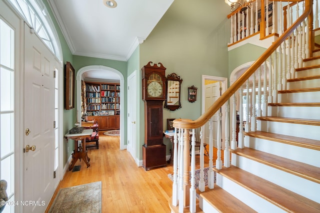 entryway with light hardwood / wood-style flooring and crown molding