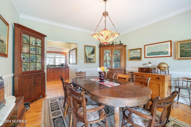 dining area with light hardwood / wood-style floors and ornamental molding