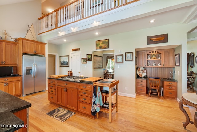 kitchen with a high ceiling, stainless steel appliances, and light hardwood / wood-style flooring