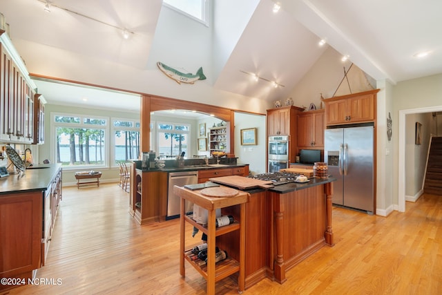 kitchen with a center island, high vaulted ceiling, rail lighting, light hardwood / wood-style flooring, and appliances with stainless steel finishes