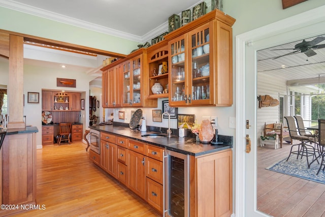 kitchen featuring ceiling fan, sink, beverage cooler, crown molding, and light hardwood / wood-style floors