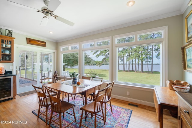 dining room featuring wine cooler, light hardwood / wood-style flooring, a wealth of natural light, and crown molding