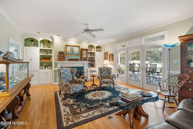 living room featuring french doors, light hardwood / wood-style flooring, ceiling fan, and crown molding