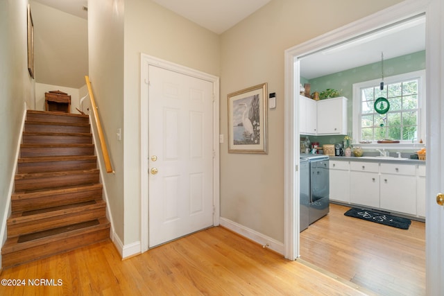 foyer with washing machine and dryer, sink, and light wood-type flooring