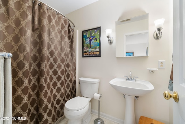 bathroom featuring tile patterned flooring, toilet, and walk in shower