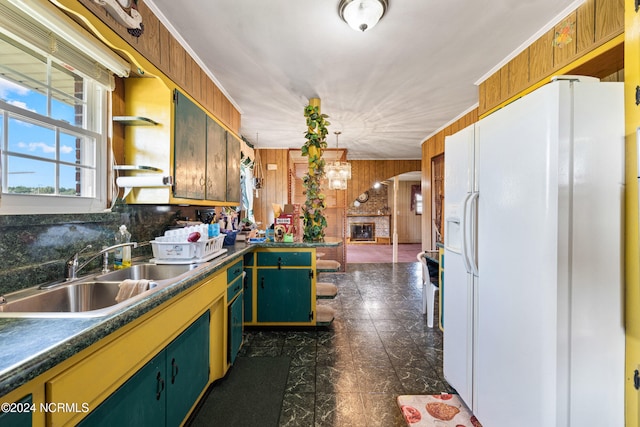 kitchen with wood walls, sink, backsplash, white refrigerator with ice dispenser, and a brick fireplace