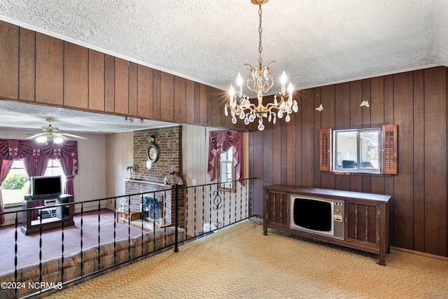 interior space with light colored carpet, wooden walls, ceiling fan with notable chandelier, and a textured ceiling