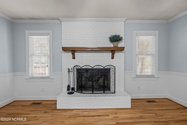 living room featuring a brick fireplace, ornamental molding, hardwood / wood-style floors, and a textured ceiling