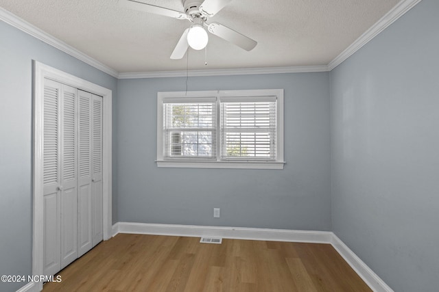 unfurnished bedroom with ceiling fan, a closet, light hardwood / wood-style floors, crown molding, and a textured ceiling