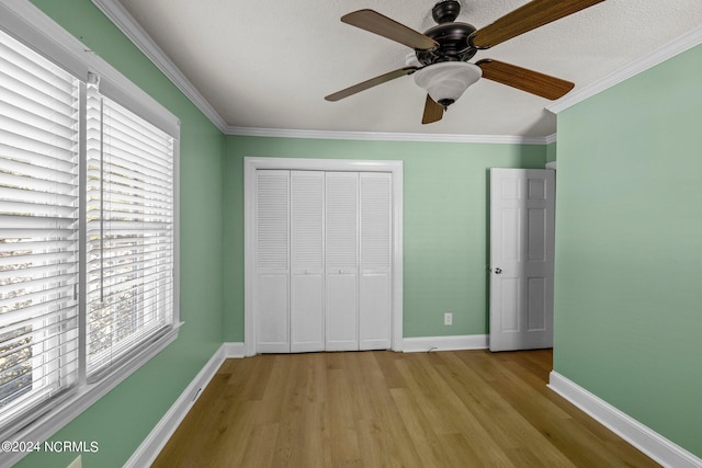 unfurnished bedroom with a closet, multiple windows, light wood-type flooring, and ceiling fan