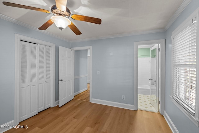 unfurnished bedroom featuring ensuite bathroom, multiple windows, ceiling fan, and light hardwood / wood-style flooring