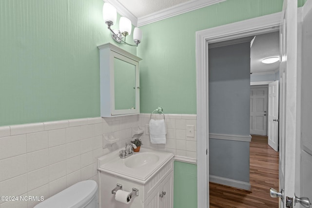 bathroom featuring toilet, crown molding, hardwood / wood-style floors, tile walls, and vanity