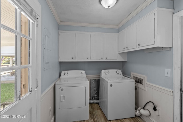 clothes washing area featuring cabinets, wood-type flooring, washer and dryer, crown molding, and a textured ceiling