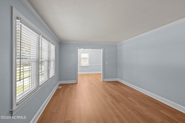 unfurnished room with ornamental molding, light wood-type flooring, and a textured ceiling