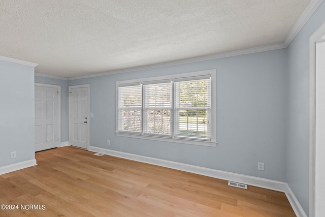 spare room featuring ornamental molding, light hardwood / wood-style flooring, and a textured ceiling