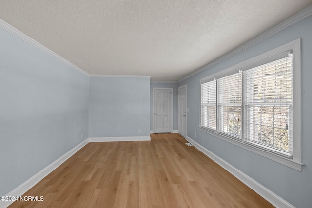 empty room with ornamental molding, light hardwood / wood-style floors, and a textured ceiling