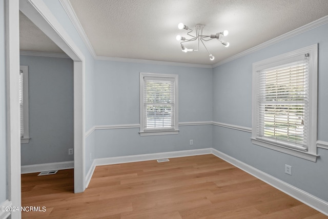 unfurnished room featuring a chandelier, light hardwood / wood-style flooring, a wealth of natural light, and a textured ceiling