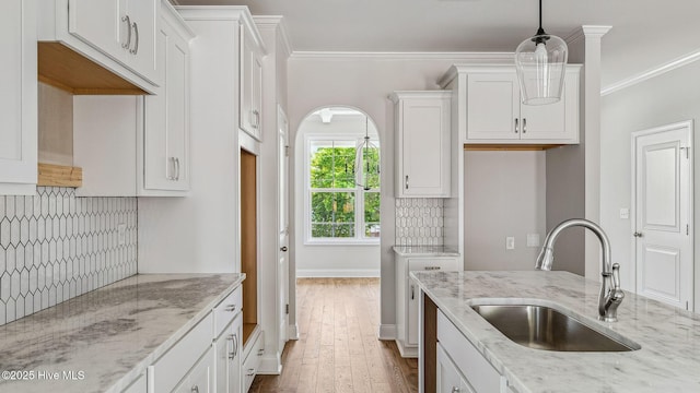 kitchen with a sink, white cabinetry, decorative backsplash, and light stone counters