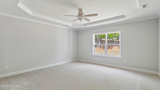 empty room featuring a ceiling fan, a tray ceiling, visible vents, light colored carpet, and ornamental molding