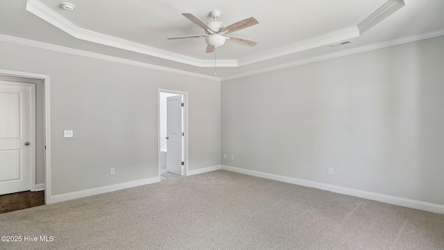 carpeted empty room featuring ceiling fan, visible vents, a raised ceiling, and ornamental molding