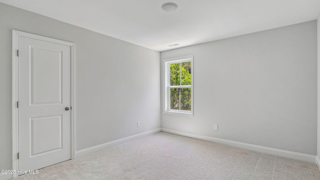 spare room with carpet floors, baseboards, and visible vents
