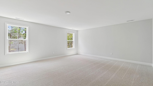 spare room with light colored carpet, visible vents, and baseboards