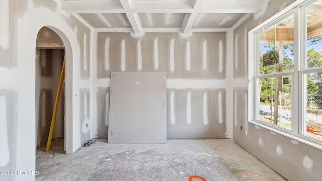 empty room with beam ceiling, a healthy amount of sunlight, and coffered ceiling